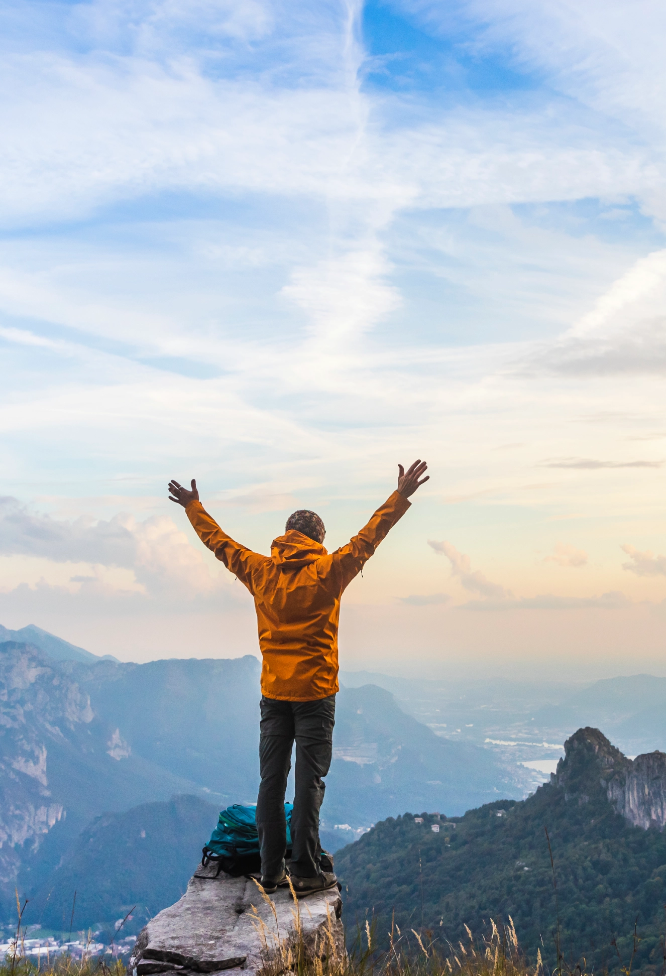 Person celebrating on mountain peak at sunrise.