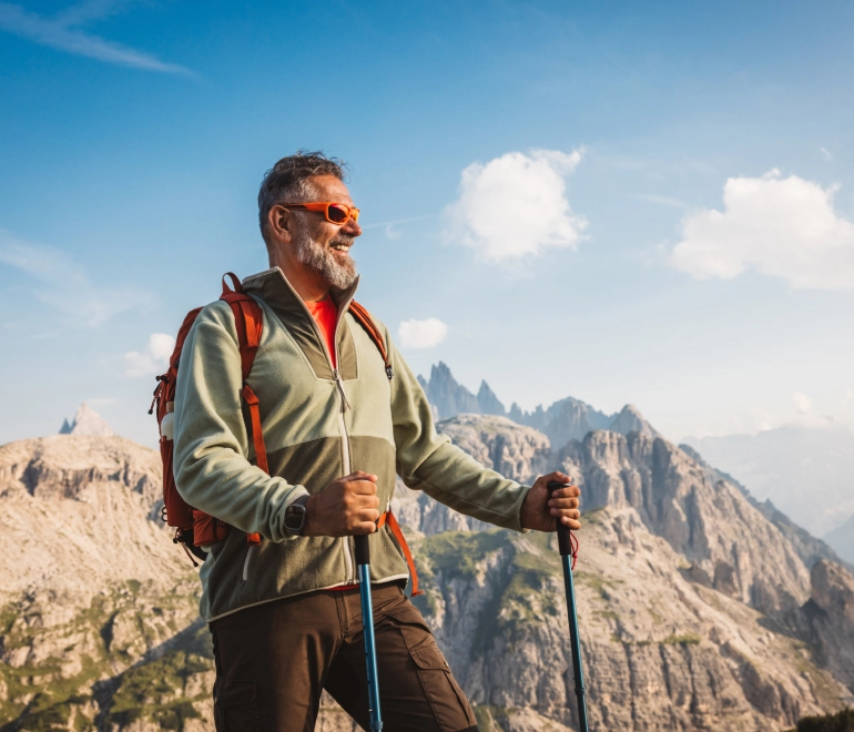 Man hiking in mountainous landscape, wearing sunglasses.