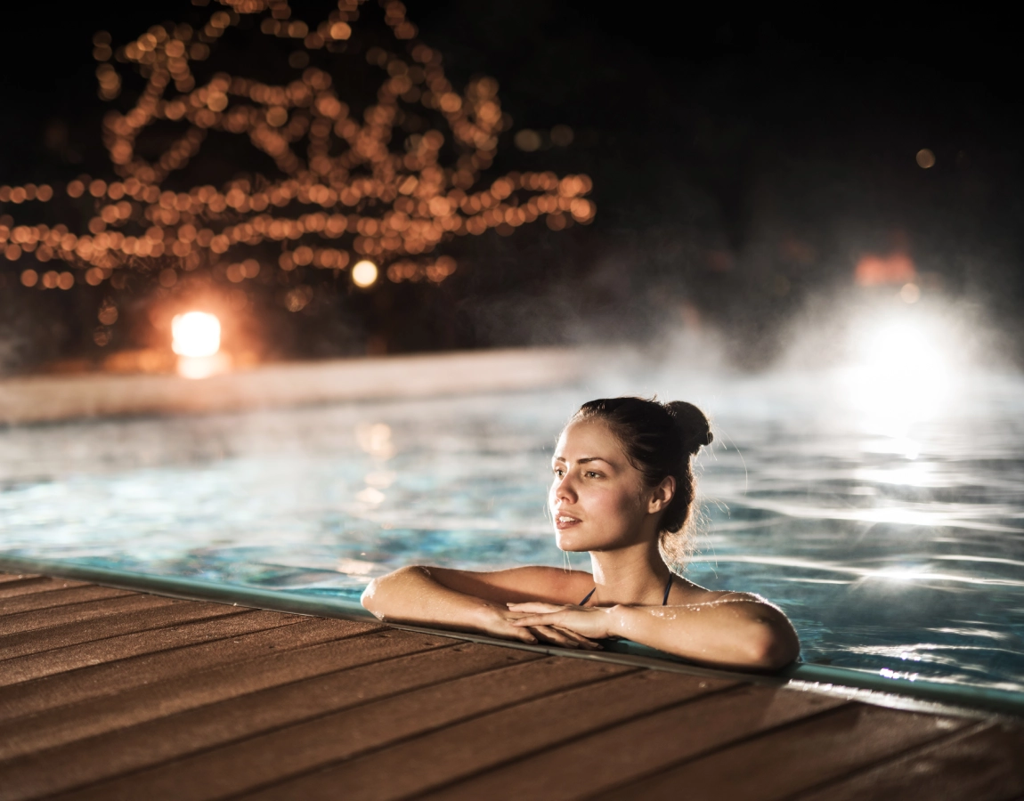 Woman relaxing in a pool at night.
