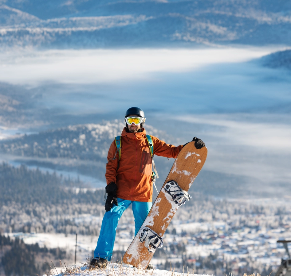 Snowboarder posing on snowy mountain landscape.