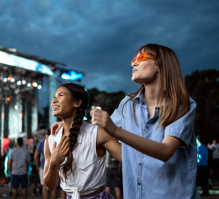 Two friends enjoying an outdoor concert.