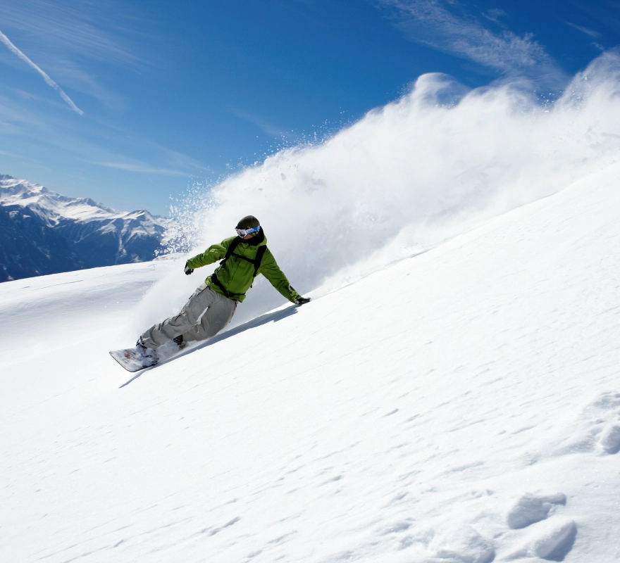 Snowboarder carving down snowy mountain slope.