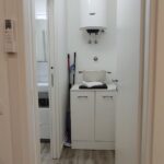 Laundry room with water heater and mop.