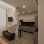 Modern studio apartment with kitchen and seating area.