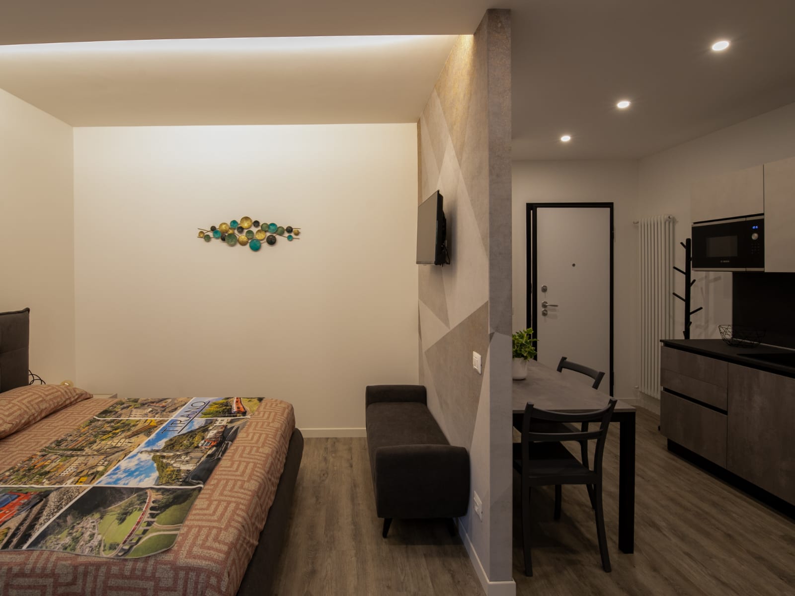 Modern studio apartment with bed and kitchenette.