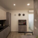 Modern kitchen with wall clocks and cabinets.