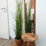 Wooden stool, mirror, plant, and rug setup.