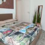 Bedroom with colorful bedspread and mirror.