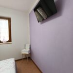 Bedroom with purple wall and mounted TV.