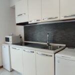 Modern kitchen with white cabinets and appliances.