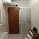 Small bathroom with shower and wooden door.