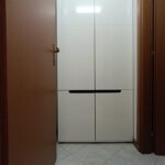 White cabinet viewed through open wooden door.