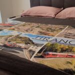 Bed with Tirano-themed blanket and pillows.